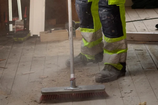 Staub wird aufgefegt, die beim Bau entstanden sind und Teil der Baureinigung ist.